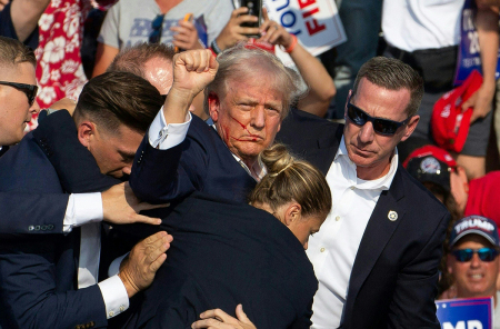 Republican candidate Donald Trump is seen with blood on his face surrounded by secret service agents as he is taken off the stage at a campaign event at Butler Farm Show Inc. in Butler, Pennsylvania, July 13, 2024. Donald Trump was hit in the ear in an assassination attempt by a gunman at a campaign rally on Saturday, in a chaotic and shocking incident that will fuel fears of instability ahead of the 2024 U.S. presidential election. The 78-year-old former president was rushed off stage with blood smeared across his face after the shooting in Butler, Pennsylvania, while the gunman and a bystander were killed and two spectators critically injured. 