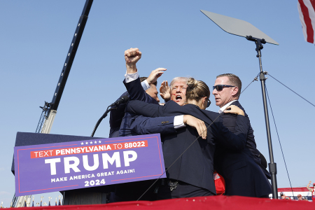 Republican presidential candidate former President Donald Trump is rushed offstage after an assassination attempt on his life during a rally on July 13, 2024, in Butler, Pennsylvania. Butler County district attorney Richard Goldinger said the shooter is dead after injuring former U.S. President Donald Trump, killing one audience member and injuring another in the shooting.