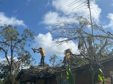 Volunteers with Texans on Mission assist a homeowner clear debris off a roof in the aftermath of Hurricane Beryl in Freeport, Texas, in July 2024. 