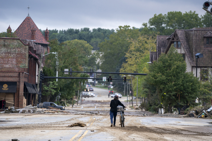 A person inspects the Biltmore Village with bicycle in the aftermath of Hurricane Helene on Sept. 28, 2024, in Asheville, North Carolina. 