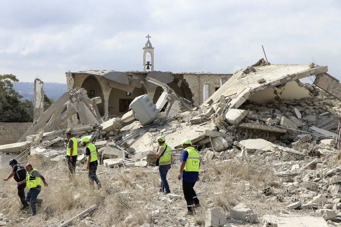 Rescuers walk near a destroyed church as they check the site of an overnight Israeli airstrike that targeted the southern Lebanese village of Derdghaiya on Oct. 10, 2024, amid the war between Israel and Hezbollah. 