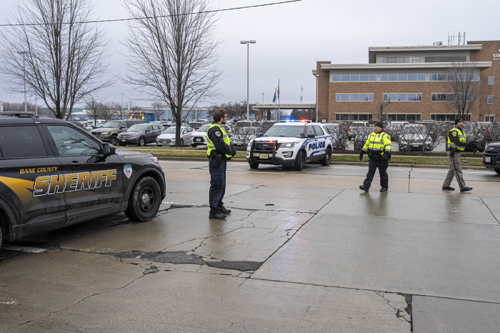 Law enforcement stand near a healthcare clinic where students from Abundant Life Christian School will be reunited withe their parents after a school shooting on Dec. 16, 2024, in Madison, Wisconsin. According to authorities, a juvenile opened fire in the school killing at least two and injuring at least six more people. The suspect was found dead inside the school by police. 