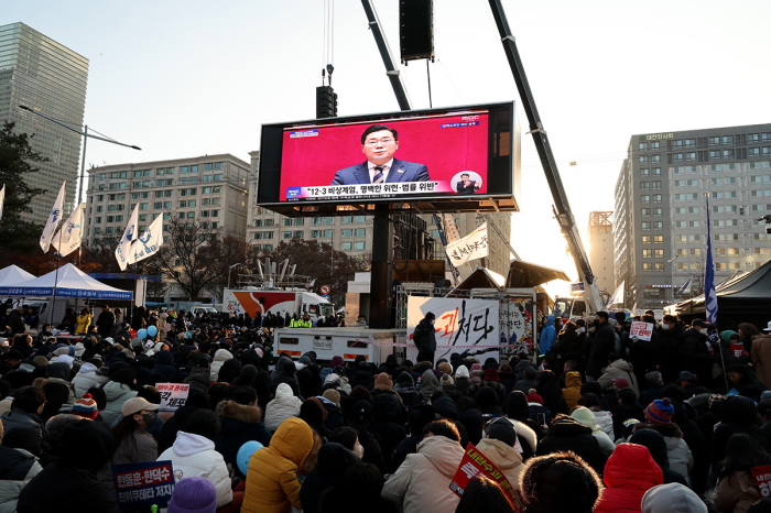 Protesters watch televised coverage as the parliament votes to impeach South Korean President Yoon Suk-yeol over his decision to impose a martial law, in front of National Assembly on Dec. 14, 2024, in Seoul, South Korea. The impeachment vote requires the backing of eight members of the ruling People Power Party (PPP) to achieve the two-thirds majority necessary to pass. 