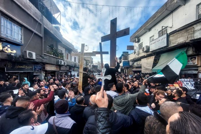 Christian Syrians lift crosses as they rally in the Duweilaah area of Damascus on Dec. 24, 2024, to protest the burning of a Christmas tree near Hama in central Syria. 