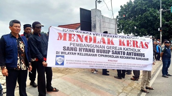 Muslim residents with banner saying they reject the construction of a Catholic church building in Cipamokolan village, Indonesia. 