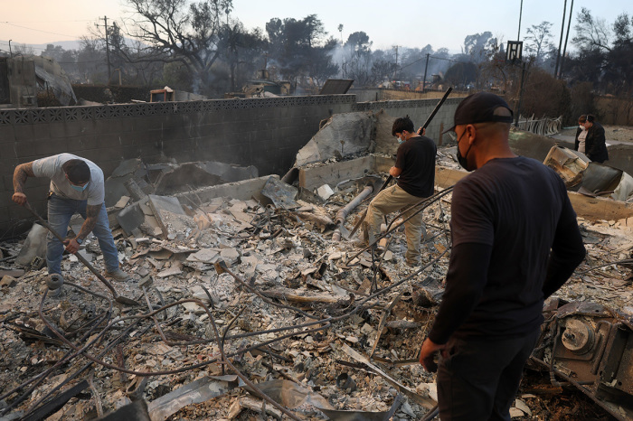 Residents dig through the remains of their family's home that was destroyed by the Eaton Fire on Jan. 09, 2025, in Altadena, California. Fueled by intense Santa Ana winds, the Eaton Fire has grown to over 10,000 acres and has destroyed many homes and businesses. 