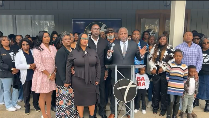 Pastor Vincent Bishop (left of podium) stands with his congregants and attorney, Jerome Carter (podium), at Destiny Worship Center in December 2024.