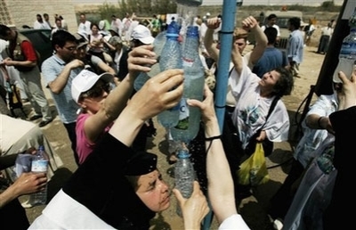 Orthodox Christian pilgrims fill up bottles of water from the Jordan River during a baptism ceremony in the waters of the Jordan River at Qasr-el Yahud near Jericho, West Bank, during Holy Week, Tuesday, April 22, 2008. The site is believed by many to be the baptismal site of Jesus.