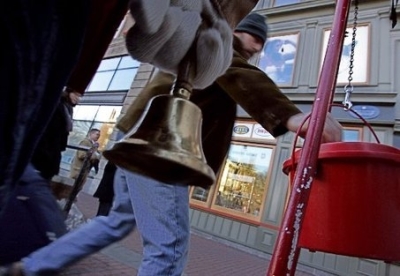 In this undated file photo, a Salvation Army volunteer rings the bell as a passer-by puts money in a red kettle at Harvard Square in Cambridge, Mass.