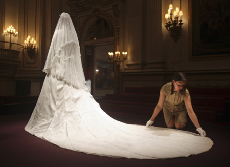 Exhibition curator, Caroline de Guitaut, adjusts the wedding dress of Britain's Catherine, Duchess of Cambridge, at Buckingham Palace in London July 20, 2011. Buckingham Palace expects record crowds this summer as up to 650,000 people are set to file into Queen Elizabeth's London residence and past the dress worn by Kate Middleton at her royal wedding to Prince William. The ivory and white garment, designed by Sarah Burton for Alexander McQueen, won over the fashion press and public when Middleton, now the Duchess of Cambridge and a future queen, walked up the aisle of Westminster Abbey in April.