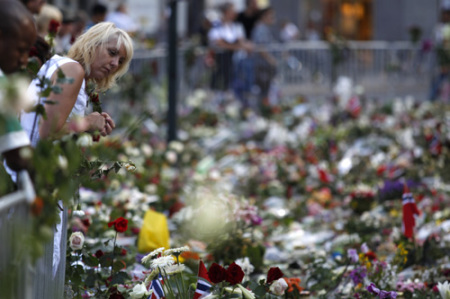 A woman pays her respects for the victims of last Friday's attacks in front of a sea of flowers outside the Oslo cathedral July 29, 2011. Flags around the nation flew at half mast to mark a day of memorial one week after Anders Behring Breivi, an anti-Islam zealot, set off a bomb in central Oslo that killed 8 people. He then shot 68 people at a summer camp for youths of the ruling Labour Party.