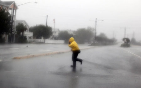 A pedestrian crosses an open area as Hurricane Irene passes through Wrightsville Beach, North Carolina August 27, 2011. Hurricane Irene howled ashore in North Carolina with heavy winds, rain and surf on Saturday on a path threatening the densely populated U.S. East Coast with flooding and power outages.