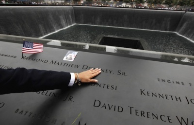 Family members of the victims of the 9/11 Attacks touch the bronze plaques that bear the names of the victims that line the perimeter of the 9/11 Memorial South Pool during the dedication ceremony for the 9/11 National Memorial and tenth 9/11 Attacks anniversary ceremonies at the World Trade Center site in New York, September 11, 2011. 