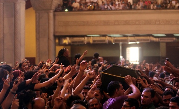 Egyptian Coptic Christians carry coffins during a mass funeral for victims of sectarian clashes with soldiers and riot police at a protest against an attack on a church in southern Egypt at Abassaiya Cathedral in Cairo