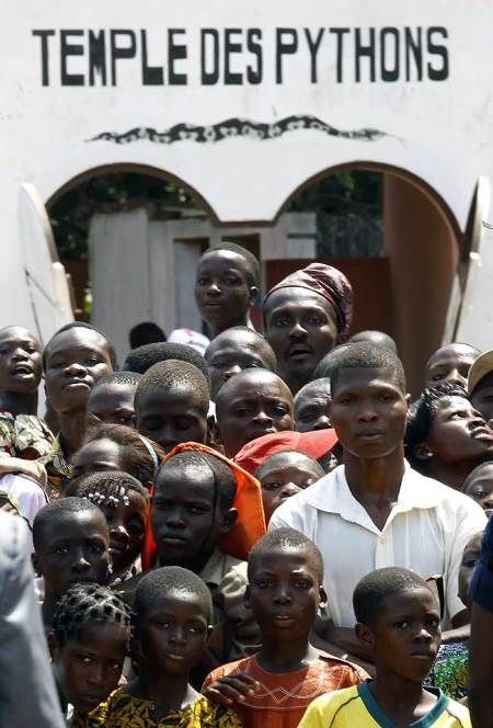 People outside a voodoo temple watch as Pope Benedict XVI arrives at Basilica of the Immaculate Conception across the street during his pastoral visit in Ouidah on Nov. 19, 2011.