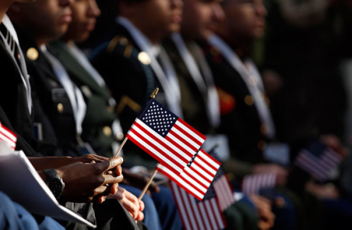 New U.S. citizens hold American flags as they take the oath of citizenship during a naturalization ceremony beneath the Statue of Liberty during ceremonies marking the 125th anniversary of the Statue at Liberty Island in New York, October 28, 2011.