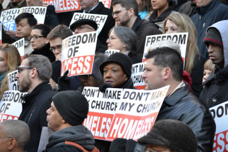 Members of Bronx Household of Faith church hold up signs Thursday at a rally supporting a resolution to overturn a policy banning worship meetings at New York City's public schools.