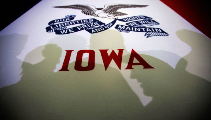 Potential caucus voters cast shadows on an Iowa state flag at a campaign rally for Republican presidential candidate and former Massachusetts Governor Mitt Romney in Clive, Iowa January 2, 2012. The Iowa caucus will be held on January 3.