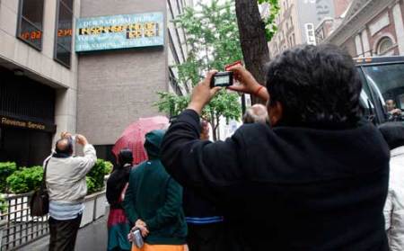 Tourists from India photograph the National Debt Clock, which displays the current United States gross national debt and each American family's share, hanging on a wall next to an office for the Internal Revenue Service near Times Square in New York May 16, 2011. The Treasury Department said the nation had hit its .294 trillion debt limit – a milestone that has little practical impact beyond injecting a note of urgency into the debate over taxes and spending that has dominated Washington this year.