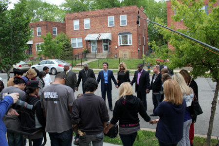 Joel and Victoria Osteen join in a circle of prayer outside of the 'New Day' Women's Transitional Home, which shelters homeless women with children, for the facility's work on Thursday, April 26, 2012, in Southeast Washington, D.C.