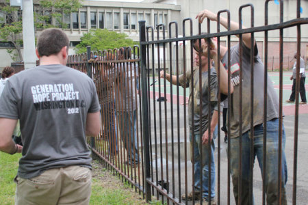 Generation Hope Project volunteers sand rusted fence rails and then repaint them as part of the renovation for Amidon-Bowen Elementary School on Thursday, April 29, 2012, in Washington, D.C.