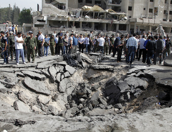 Residents and security personnel gather at the site of an explosion in Damascus May 10, 2012. Two explosions shook the Syrian capital Damascus on Thursday, killing and wounding dozens of people, state media said, in a district that houses a military intelligence complex involved in President Bashar al-Assad's crackdown on a 14-month uprising.