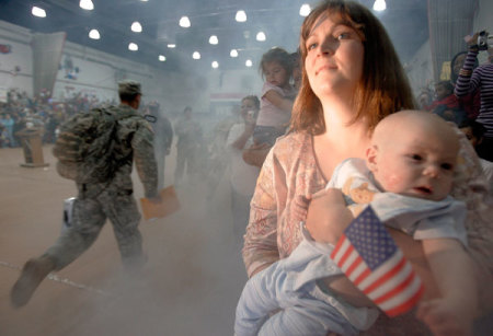 A woman watches as soldiers from the Army's 4th Infantry Division arrive at a homecoming ceremony in Fort Hood, Texas November 28, 2006. The division returned after spending a one year tour in Iraq.