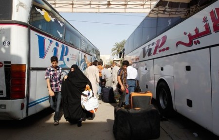 People unload their belongings from a bus that has traveled from Syria after arriving in Baghdad July 20, 2012. Iraq on Tuesday called on tens of thousands of its citizens still living in Syria to return home because of escalating violence in its neighbor, after police said two Iraqi journalists had been killed in Damascus.