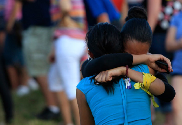 People grieve during a vigil for victims behind the theater where a gunman opened fire on moviegoers in Aurora, Colorado July 20, 2012. A total of 71 people were shot in Friday's rampage at the Denver-area movie theater that has left 12 people dead, the local police chief said.