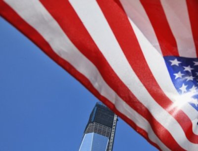 A U.S. flag flutters in front of One World Trade Center at the perimeter of its construction site in New York, September 7, 2012.