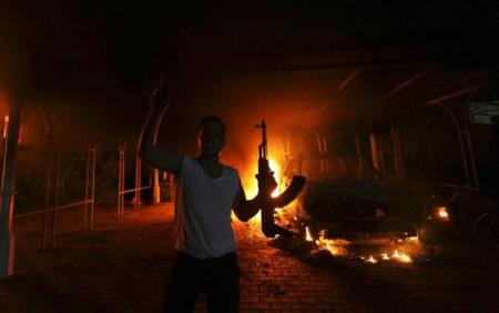 A protester reacts as the U.S. Consulate in Benghazi is seen in flames during a protest by an armed group said to have been protesting a film being produced in the United States Sept. 11, 2012. The U.S. ambassador to Libya and three other embassy staff were killed in a rocket attack on their car, a Libyan official said, as they were rushed from a consular building stormed by militants denouncing a U.S.-made film deemed insulting to the Prophet Mohammad.