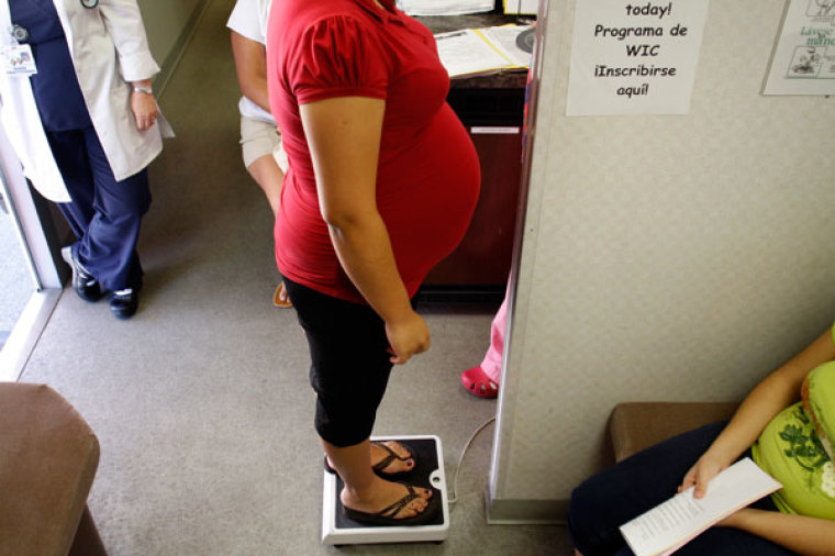 A pregnant woman stands on a scale before receiving a prenatal exam at the Maternity Outreach Mobile in Phoenix, Arizona October 8, 2009. The maternity outreach program helps uninsured women living in the Phoenix metropolitan area receive the proper treatment and care during and after their pregnancy. The Maternity Outreach Mobile is equipped with two exam rooms, an ultrasound machine, an external fetal monitor, a laboratory and offers pregnancy tests, referrals and immunization for children.