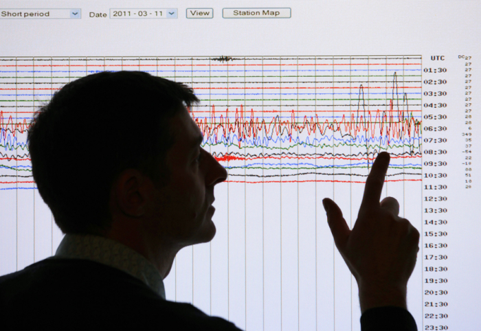 A seismologist poses for the media as he points to a seismographic graph in this 2011 file photo.