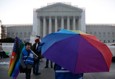 A person waits under a rainbow-colored umbrella outside of the U.S. Supreme Court in Washington, March 26, 2013. America's top court takes up the delicate and divisive issue of gay marriage on Tuesday when the nine Supreme Court justices consider the legality of a California ballot initiative that limits marriage to opposite-sex couples.