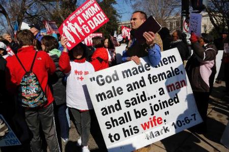 Anti-gay marriage protesters hold signs as they march in front of the U.S. Supreme Court in Washington March 26, 2013. Two members of the U.S. Supreme Court, both viewed as potential swing votes on the right of gay couples to marry, raised doubts about California's gay marriage ban on Tuesday as they questioned a lawyer defending the ban.