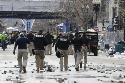 Public safety officials evacuate the scene after several explosions near the finish line of the 117th Boston Marathon in Boston, Massachusetts April 15, 2013. One or more bombs were responsible for the explosions that struck the Boston Marathon as runners crossed the finish line, two high-level law enforcement sources told Reuters.