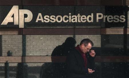 A man looks down at his smartphone as he walks past the offices of the Associated Press in Manhattan, N.Y., May 13, 2013.