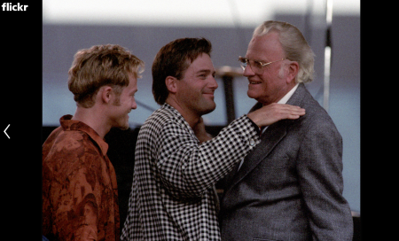 Evangelist Billy Graham, at a crusade in Cleveland Ohio, on June 11, 1994. Gets a hug from singer Michael W. Smith (in Black and White shirt) while Toby Mac, (in orange) looks on. This was the first time the Billy Graham Crusade had tried a Youth Night.