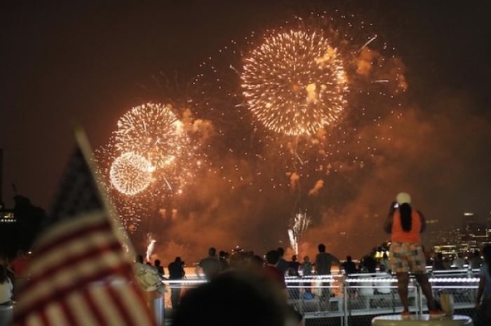 People look at fireworks exploding over the Hudson River and the skyline of New York during the Macy's Independence Day celebration as seen from Hoboken, New Jersey, July 4, 2012.