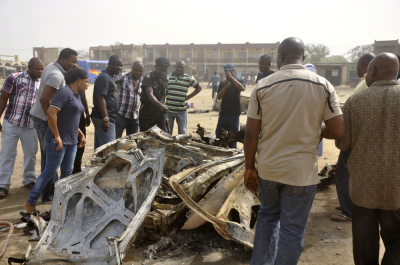 A police officer points at the wreckage of a vehicle after explosions hit Sabon Gari in Kano, Nigeria in an attack in March 2013.