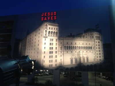 A smaller replica of the iconic 'Jesus saves' sign is incorporated into a giant mural on the side of a Biola University parking structure.