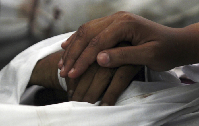 The widow of a dead Muslim Brotherhood supporter touches her husband's hand at El Eyman mosque in Cairo August 15, 2013. Egypt's Muslim Brotherhood called on followers to march in protest in Cairo on Thursday, after at least 525 people were killed in a security crackdown on the Islamist movement that has left the most populous Arab nation polarized and in turmoil. A Reuters witness counted 228 bodies, most of them wrapped in white shrouds, arranged in rows on the floor of the Imam mosque in northeast Cairo, close to the worst of Wednesday's violence between police and demonstrators.