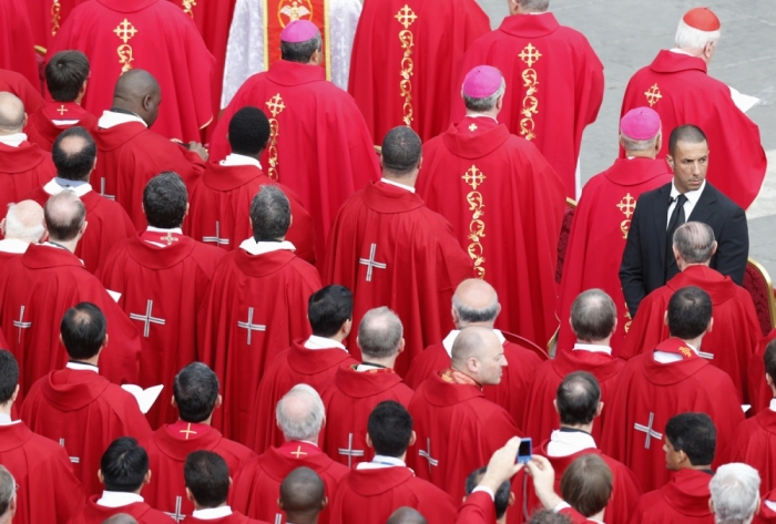 A Vatican security agent stands among the priests as Pope Francis leads a mass in Saint Peter's Square at the Vatican, May 19, 2013.