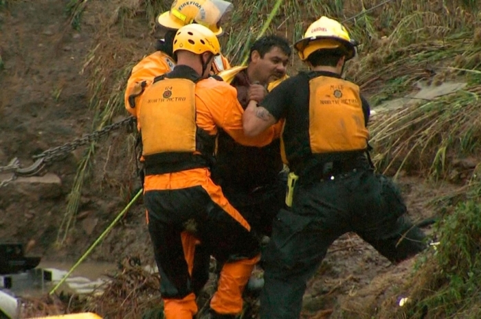 Emergency personnel work to rescue a man trapped in his vehicle during flooding of Rock Creek in Lafayette, Colo.