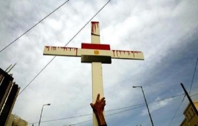 An Egyptian Coptic Christian holds a cross with the Egyptian flag during a demonstration outside the Egyptian embassy in Athens April 19, 2006.