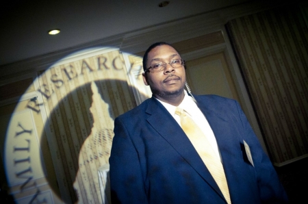 Leo Johnson, the guard who took a bullet defending the Family Research Council from a shooter in 2012, stands before the FRC banner. He said that God gave him the strength to disarm and not to kill, the attacker, Floyd Corkins II.