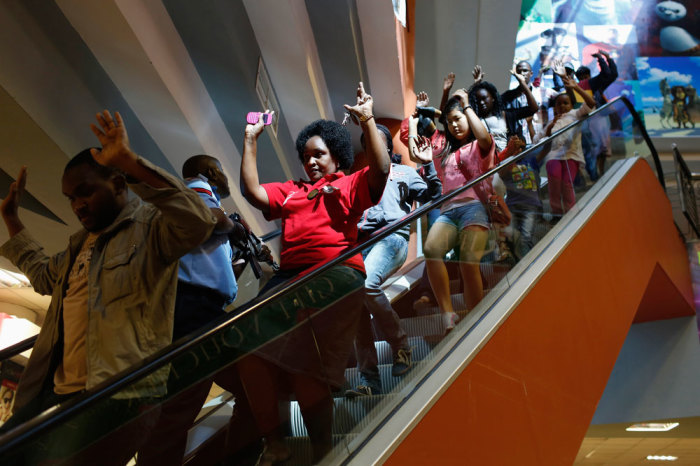 Civilians escape an area at the Westgate Shopping Centre in Nairobi September 21, 2013. Gunmen stormed the shopping mall in Nairobi on Saturday killing at least 20 people in what Kenya's government said could be a terrorist attack, and sending scores fleeing into shops, a cinema and onto the streets in search of safety. Sporadic gun shots could be heard hours after the assault started as soldiers surrounded the mall and police and soldiers combed the building, hunting down the attackers shop by shop.