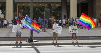 Same sex marriage supporters wave signs and flags in front of the Hawaii State Capital Sunday. Hawaii could become the 15th state to legalize gay marriage after its Senate approved legislation on Wednesday.