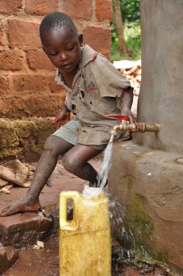 Three-year-old Nsereko Jagenda drinking water from the water jar at home with a cupped hand. from donors in the United Kingdom through World Vision UK