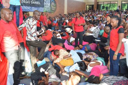 Pastor Lesego Daniel (with mic) of South Africa's Rabboni Centre Ministries walks on congregants he commanded to go to sleep.